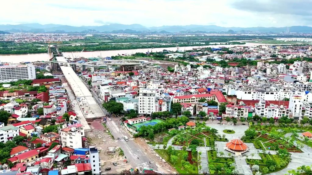 Cầu dẫn cầu Nguyễn Trãi bằng bê tông chạy thẳng qua khu dân cư mái đỏ bờ nam, bên phải là một công viên có nhà bát giác, phía xa là sông Cấm