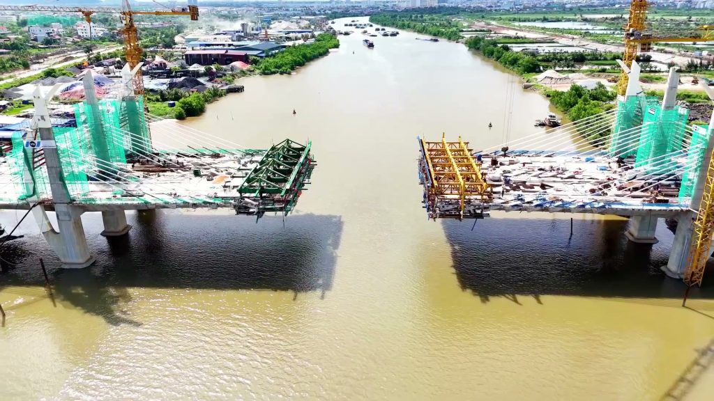 Hai nửa cầu Hải Thành vươn ra giữa sông Lạch Tray, khoảng trống ở giữa chờ hợp long, hai bên là trụ tháp phủ lưới xanh và cần cẩu