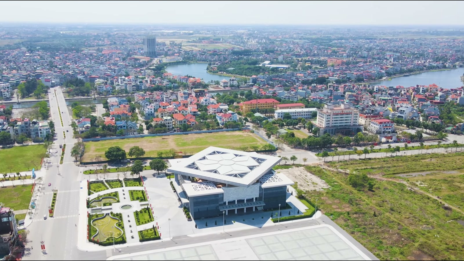 Công trình công cộng mái xếp hình ngôi sao nằm giữa khu đất trống rộng, phía trước là quảng trường và trục đường mới mở