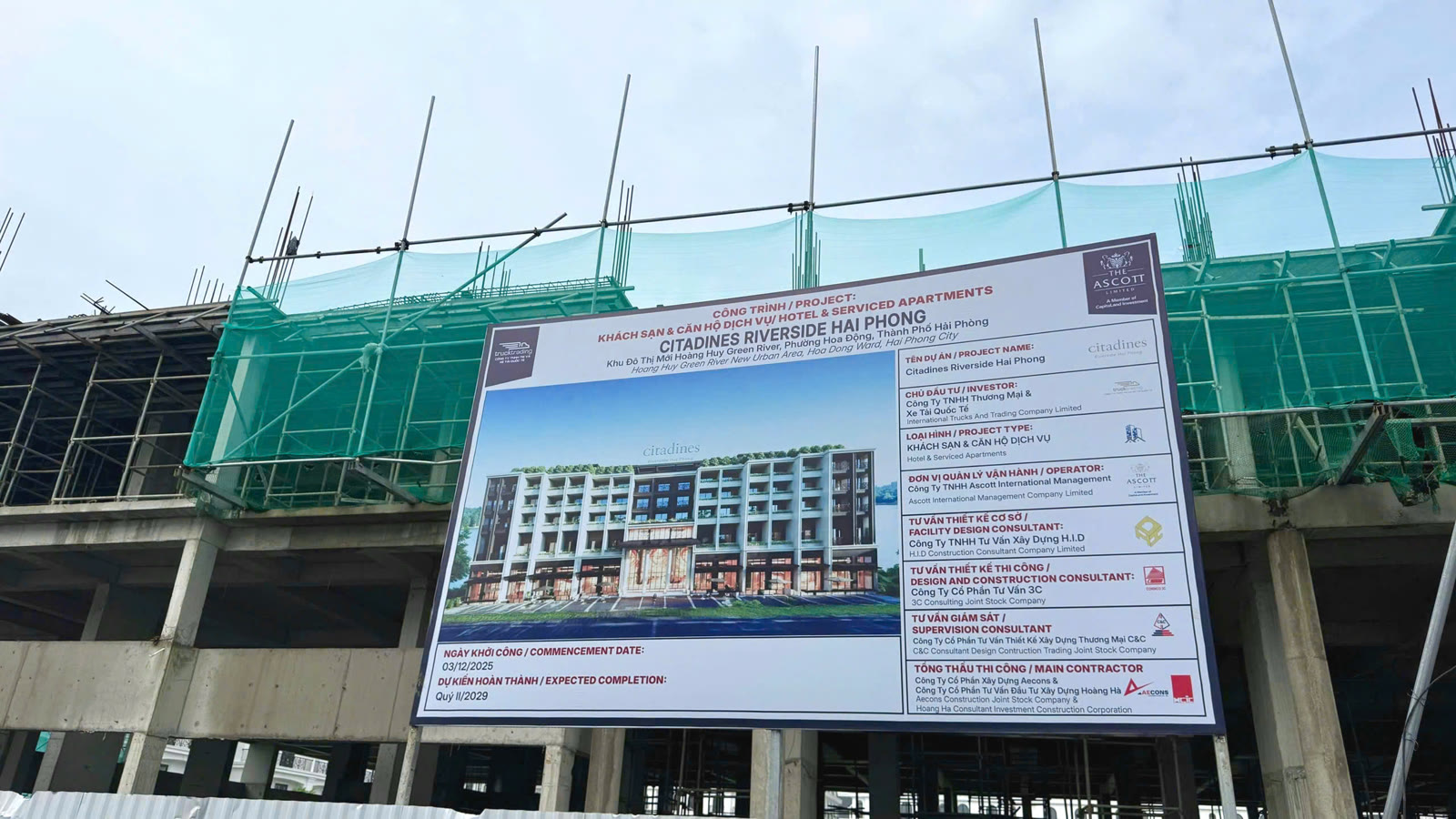 Công trường khách sạn Citadines Riverside Hải Phòng đang xây phần thân, giàn giáo phủ lưới xanh, phía trước treo bảng thông tin dự án có phối cảnh toà nhà