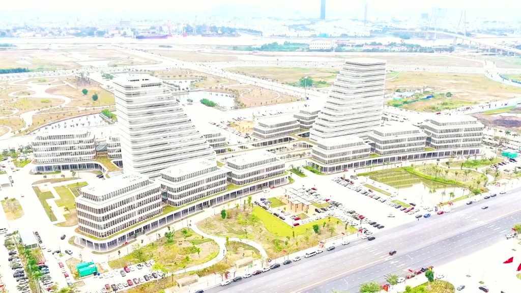 Đại lộ rộng nhiều làn xe chạy trước khu trụ sở hành chính mới ở Bắc Sông Cấm với hai toà tháp bậc thang màu trắng, phía xa là sông Cấm và cầu dây văng