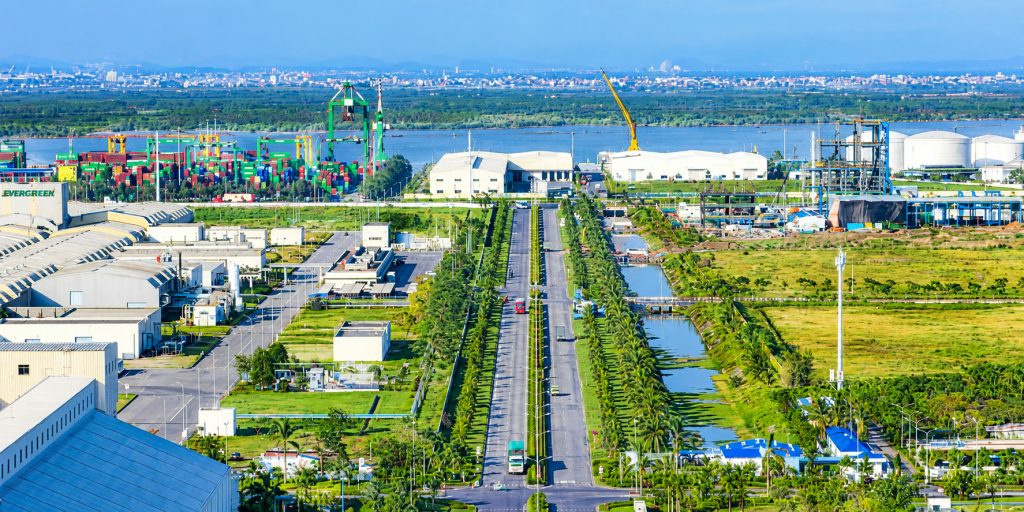 Khu công nghiệp DEEP C ở Đình Vũ nhìn từ trên cao, bên trái là bãi container và cần cẩu, bên phải là bồn chứa hoá chất, giữa là đại lộ trồng dừa