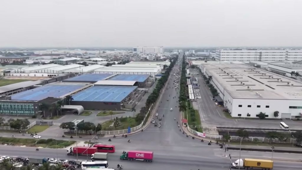 Khu công nghiệp Tràng Duệ nhìn từ trên cao với dãy nhà xưởng mái xanh và trục đường có xe container chạy qua