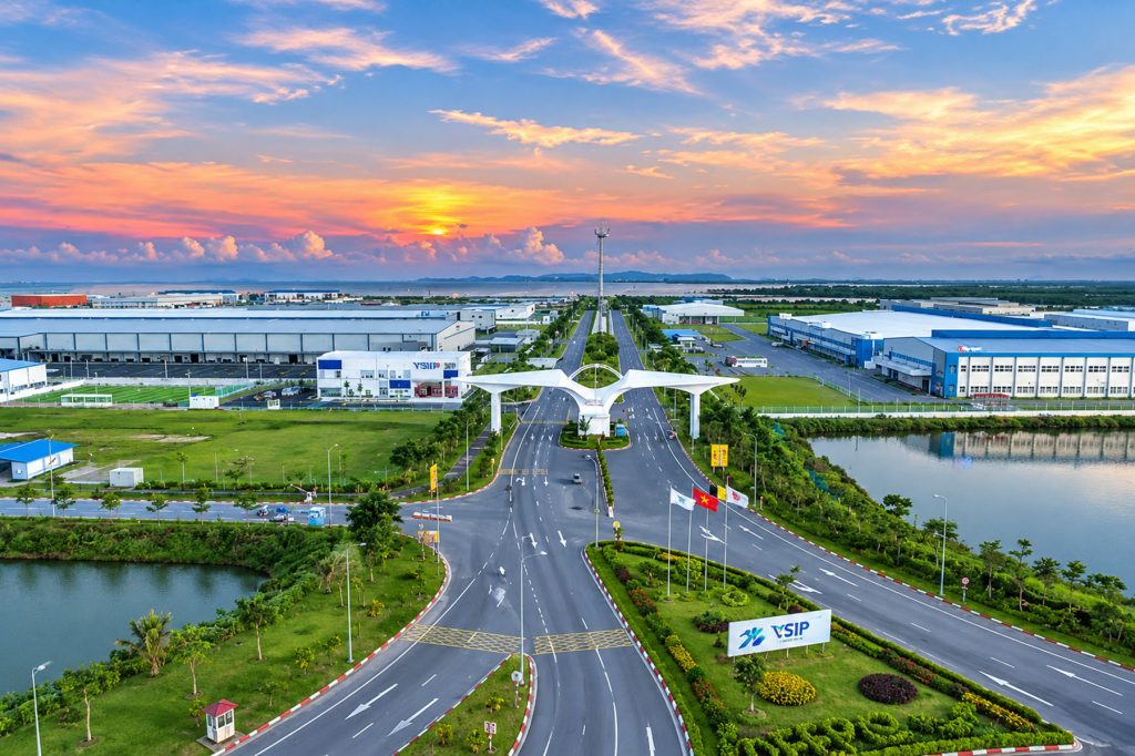 Cổng chính khu công nghiệp VSIP Hải Phòng lúc hoàng hôn, biển hiệu VSIP đặt trên thảm cỏ bên trục đường lớn dẫn vào khu