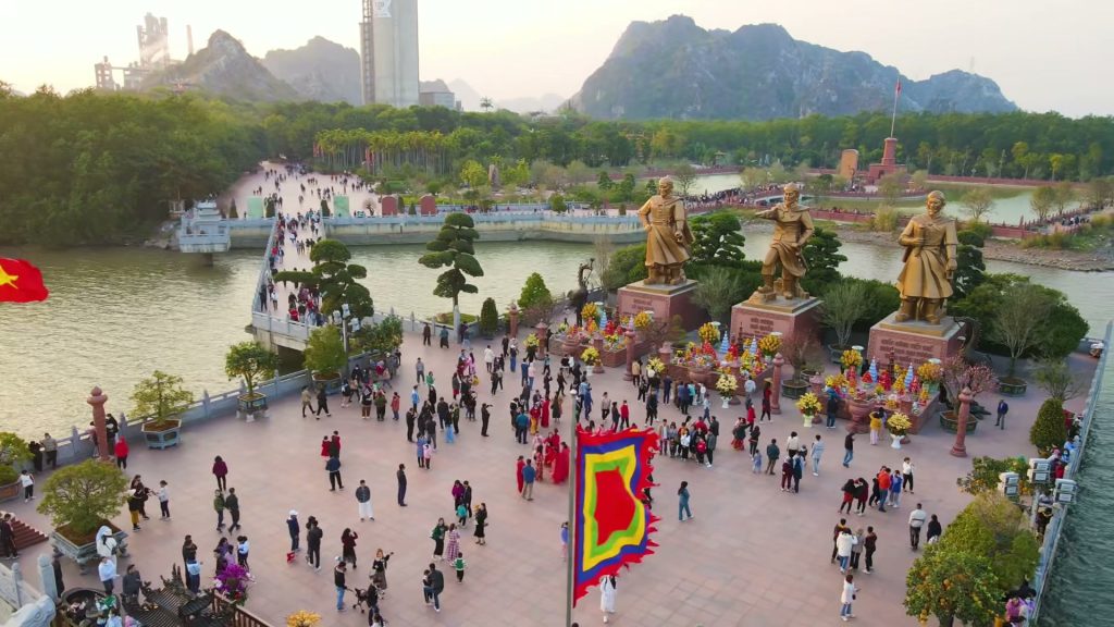 Khu di tích Bạch Đằng Giang nhìn từ trên cao, ba tượng đồng đứng bên bờ sông, quảng trường đông người tham quan, phía xa là dãy núi đá vôi Tràng Kênh