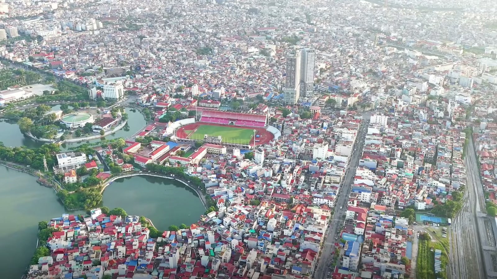 Khu phố cũ bên một hồ nước lớn nhìn từ trên cao, sân vận động nằm giữa các dãy nhà mái đỏ, xa xa là nhà cao tầng