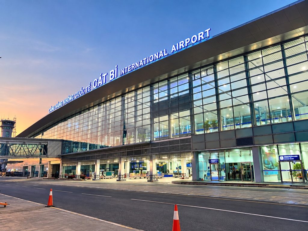 Nhà ga hành khách hiện hữu của Cảng hàng không quốc tế Cát Bi lúc chập tối, biển tên Cát Bi International Airport sáng đèn trên mái, mặt tiền kính