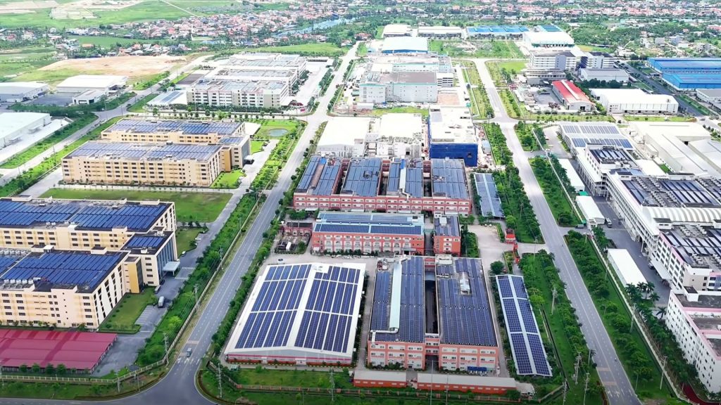 Nhà xưởng mái lợp pin mặt trời xếp thành dãy dọc các trục đường thẳng trong khu công nghiệp nhìn từ trên cao