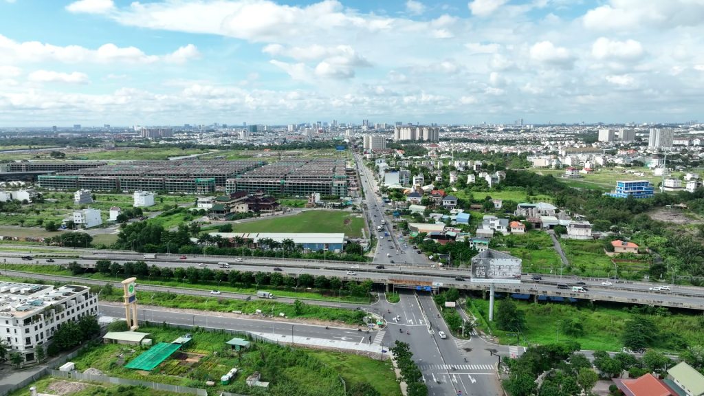 Nút giao đường bộ và khu dân cư thấp tầng nhìn từ trên cao, đồng ruộng xen giữa các trục đường mới mở