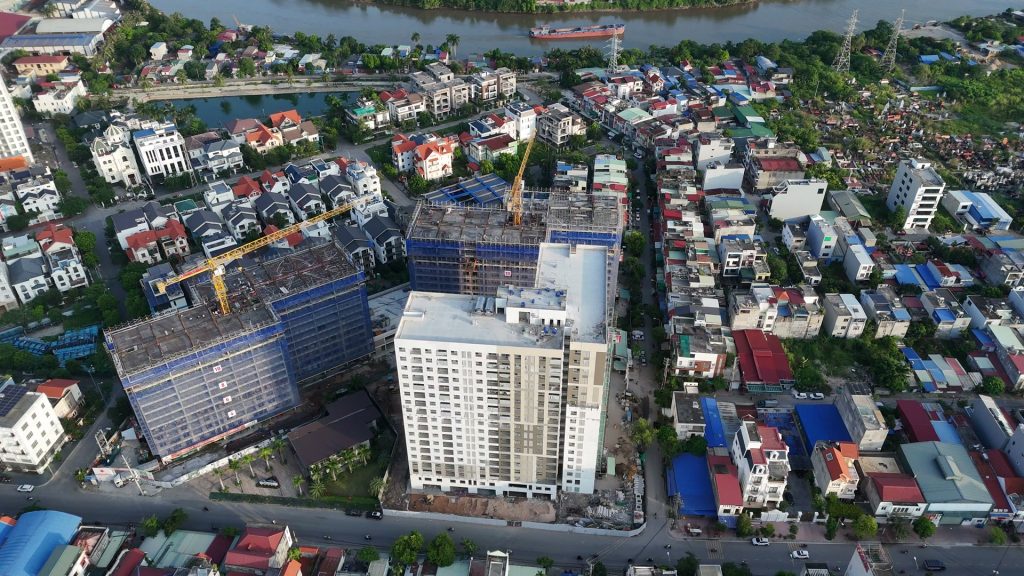 Dự án AnZen Residences nhìn từ trên cao, một tòa đã hoàn thiện màu trắng và hai tòa còn giàn giáo, phía sau là dòng sông và khu dân cư